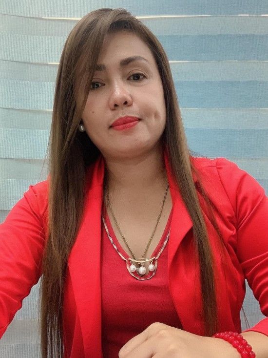 Woman with long brown hair wearing a red blazer and necklace.