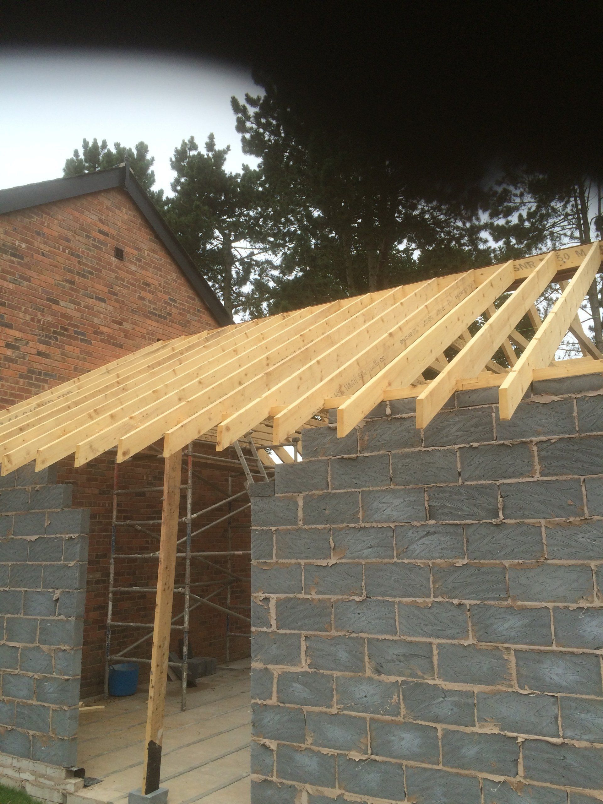 A brick building with a wooden roof under construction