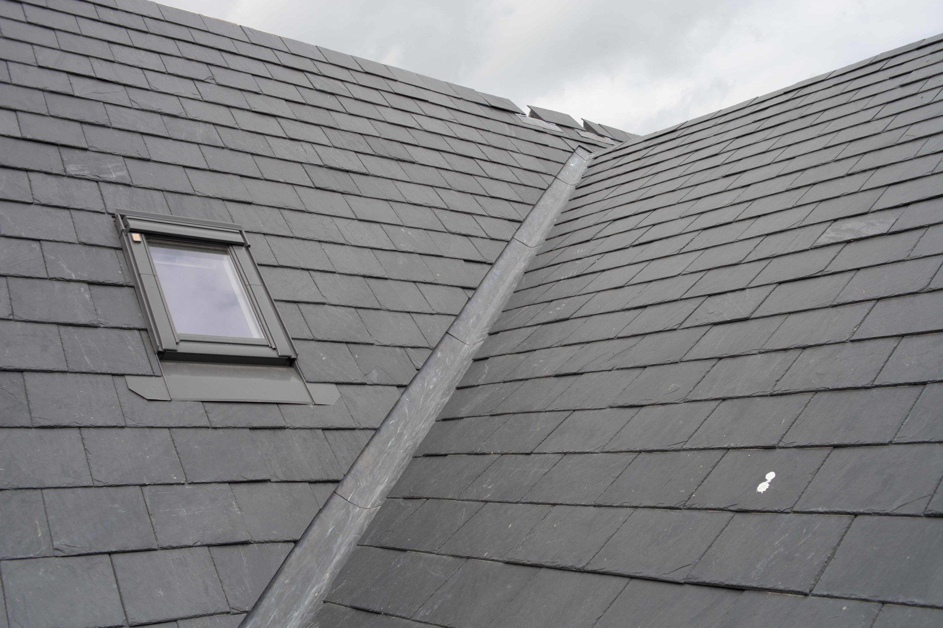 A roof with slate tiles and a skylight on it
