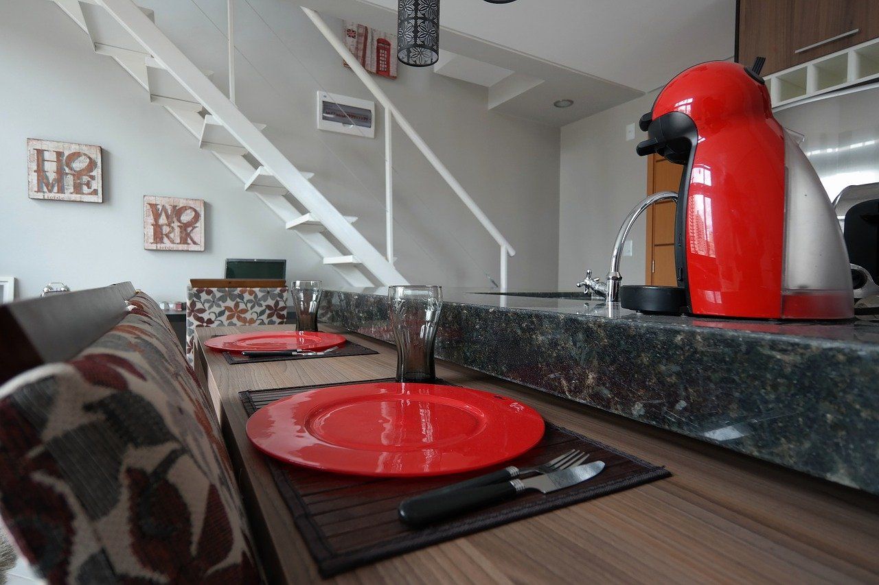 A kitchen counter with a red coffee maker and plates on it.
