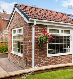 A small brick house with a hanging basket of flowers in front of it.