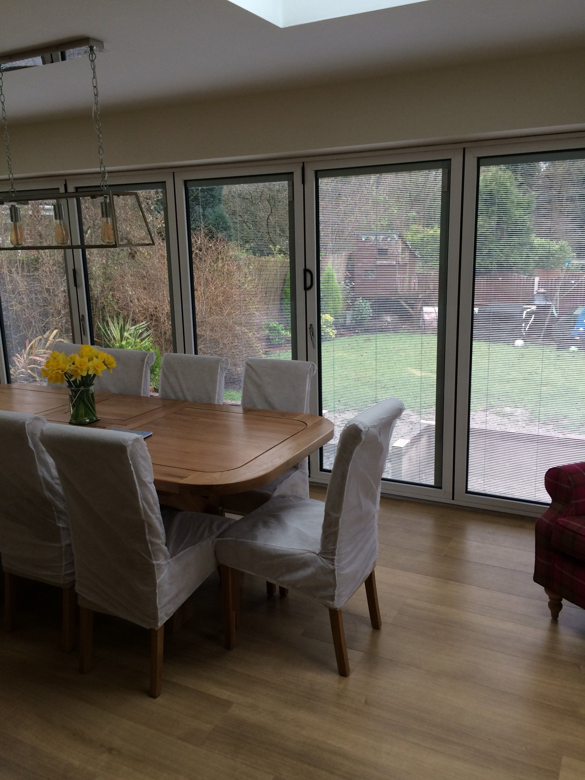 A dining room with a table and chairs and a vase of yellow flowers.