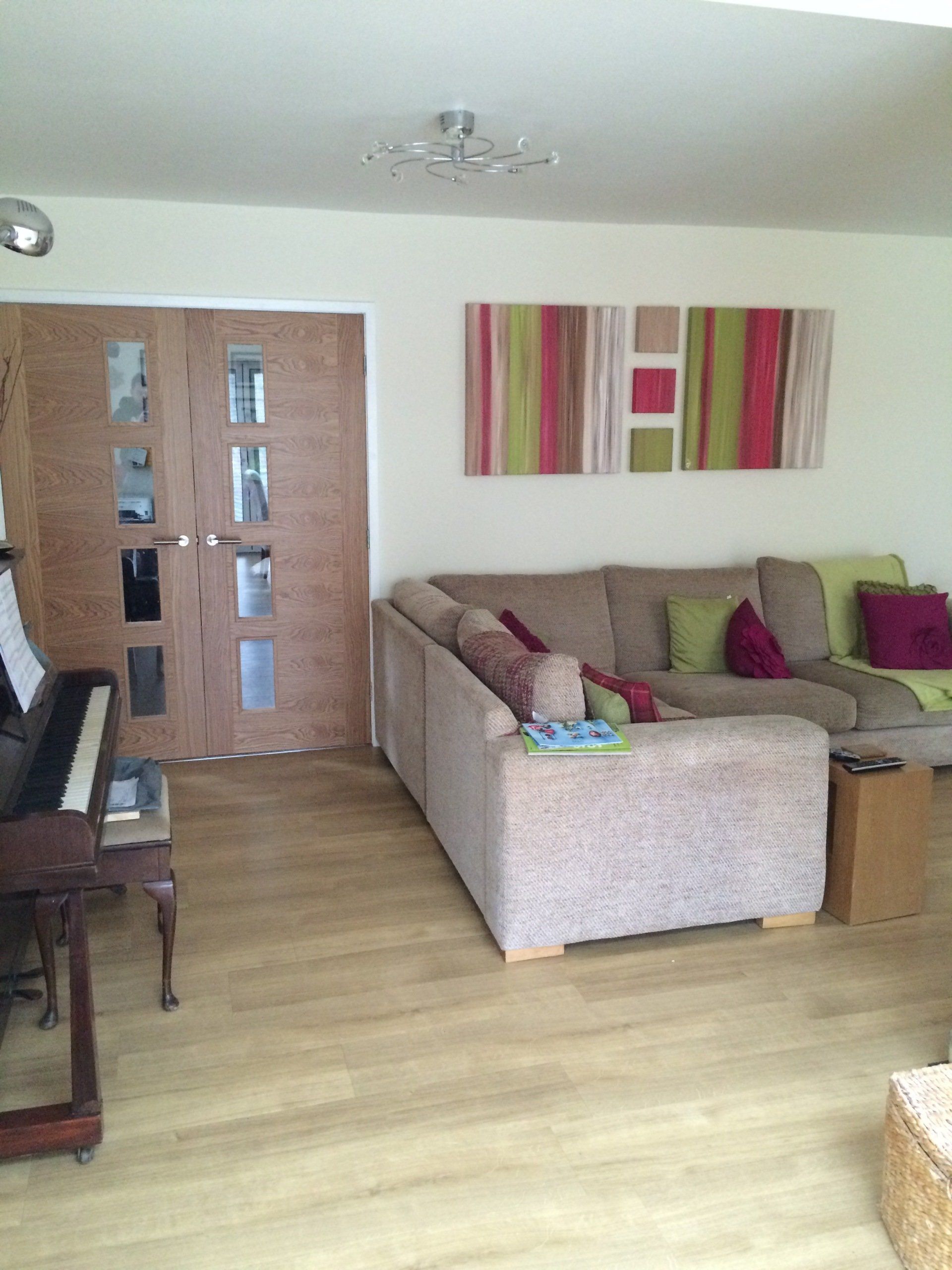 A living room with a couch , piano and paintings on the wall.