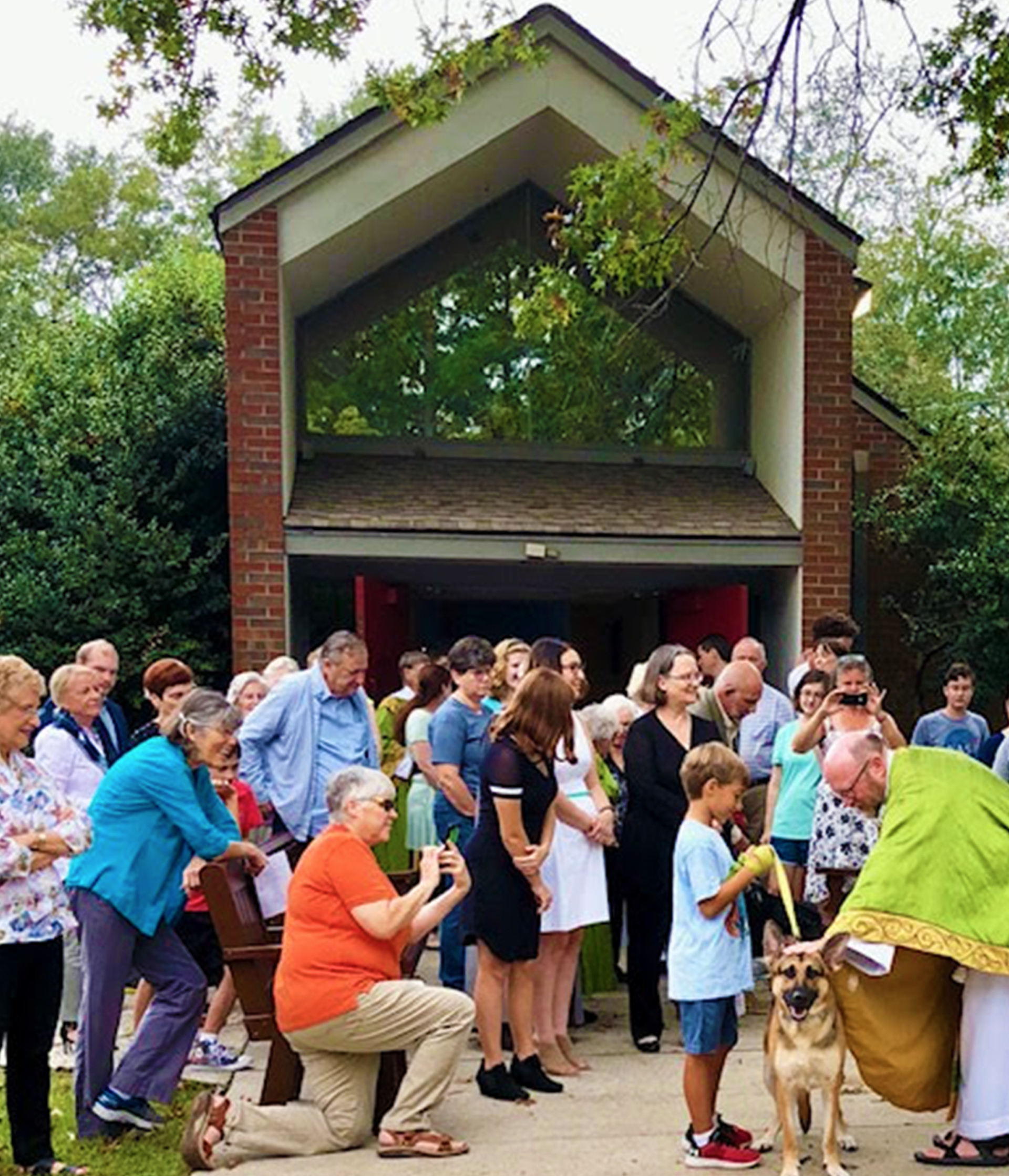 members of church gathered around a boy and his dog, which is being blessed