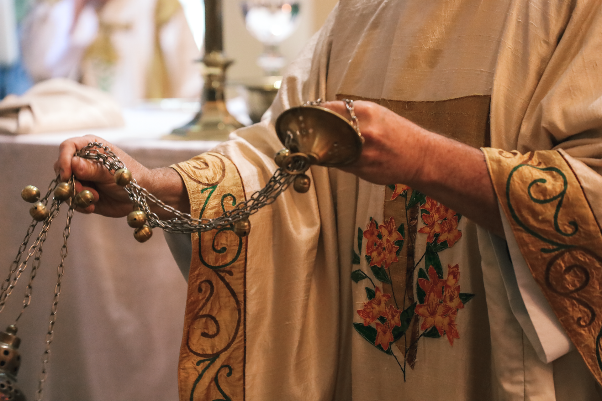 presider holding the chain of a thurifer during a church procession