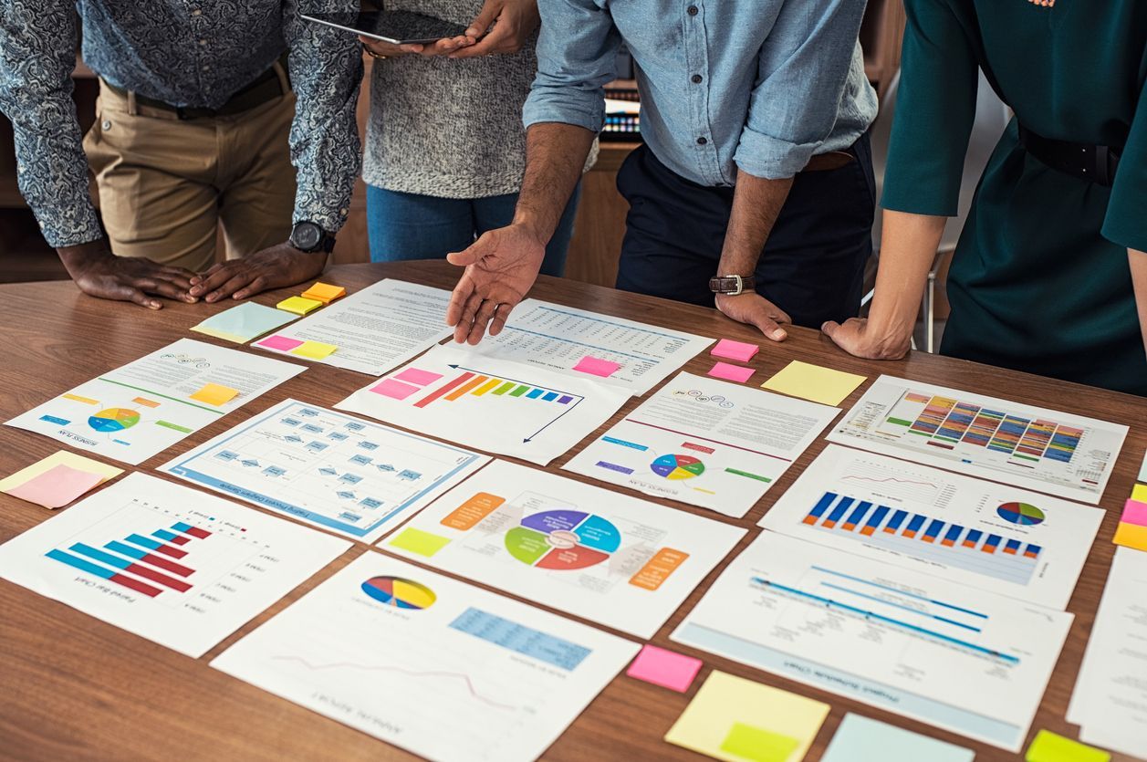 People looking at a table with lots of charts and graphs.