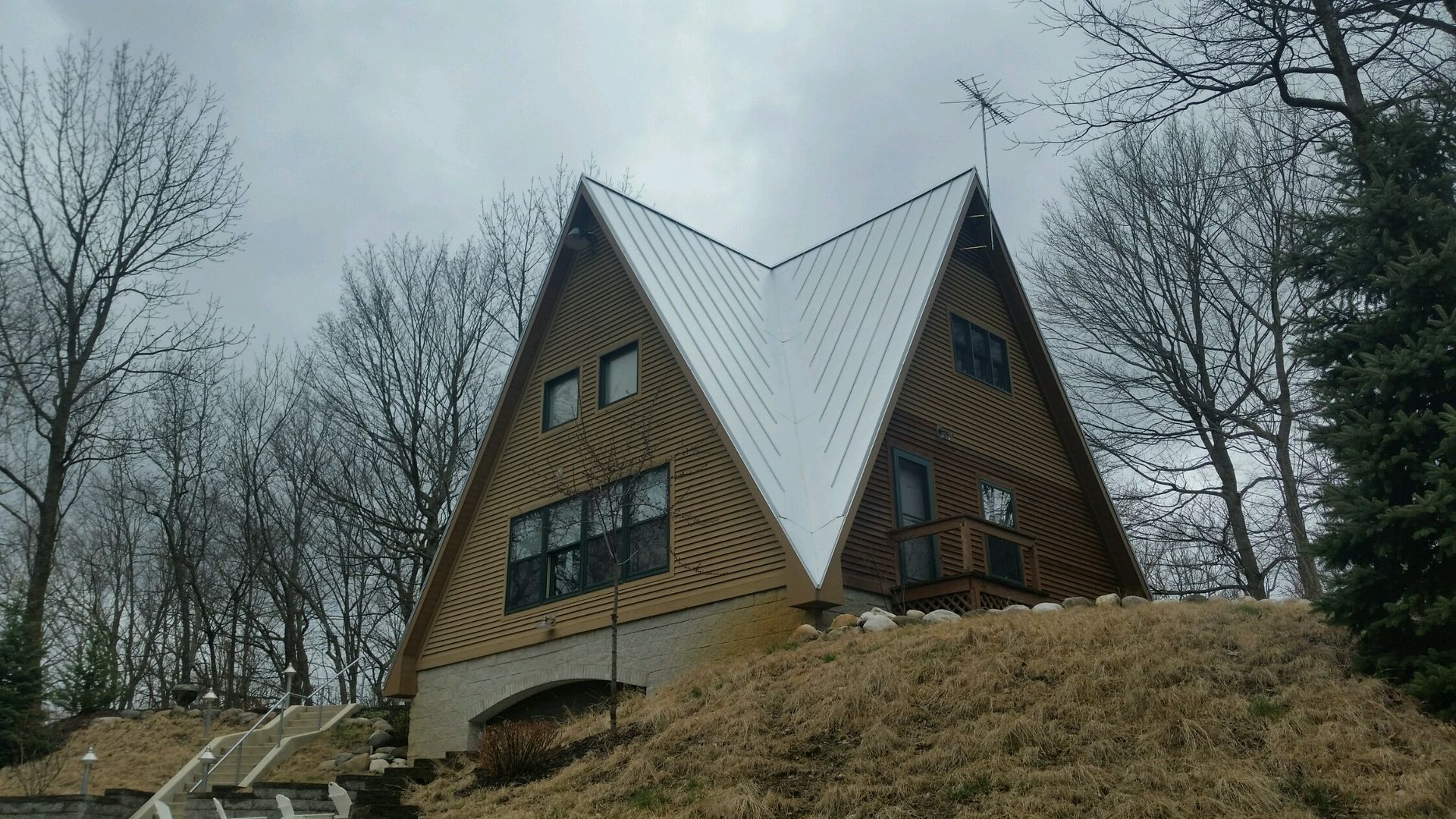 Two a frame houses are sitting on top of a grassy hill.