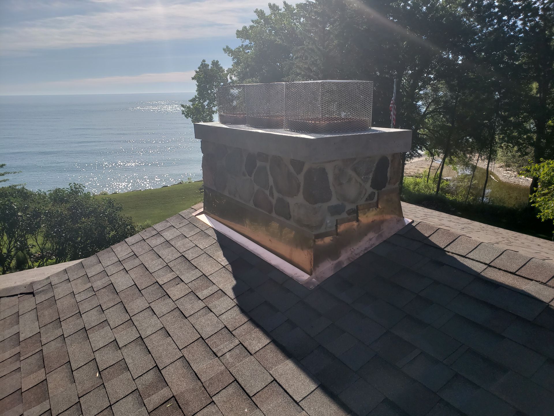 A chimney on top of a roof overlooking the ocean.