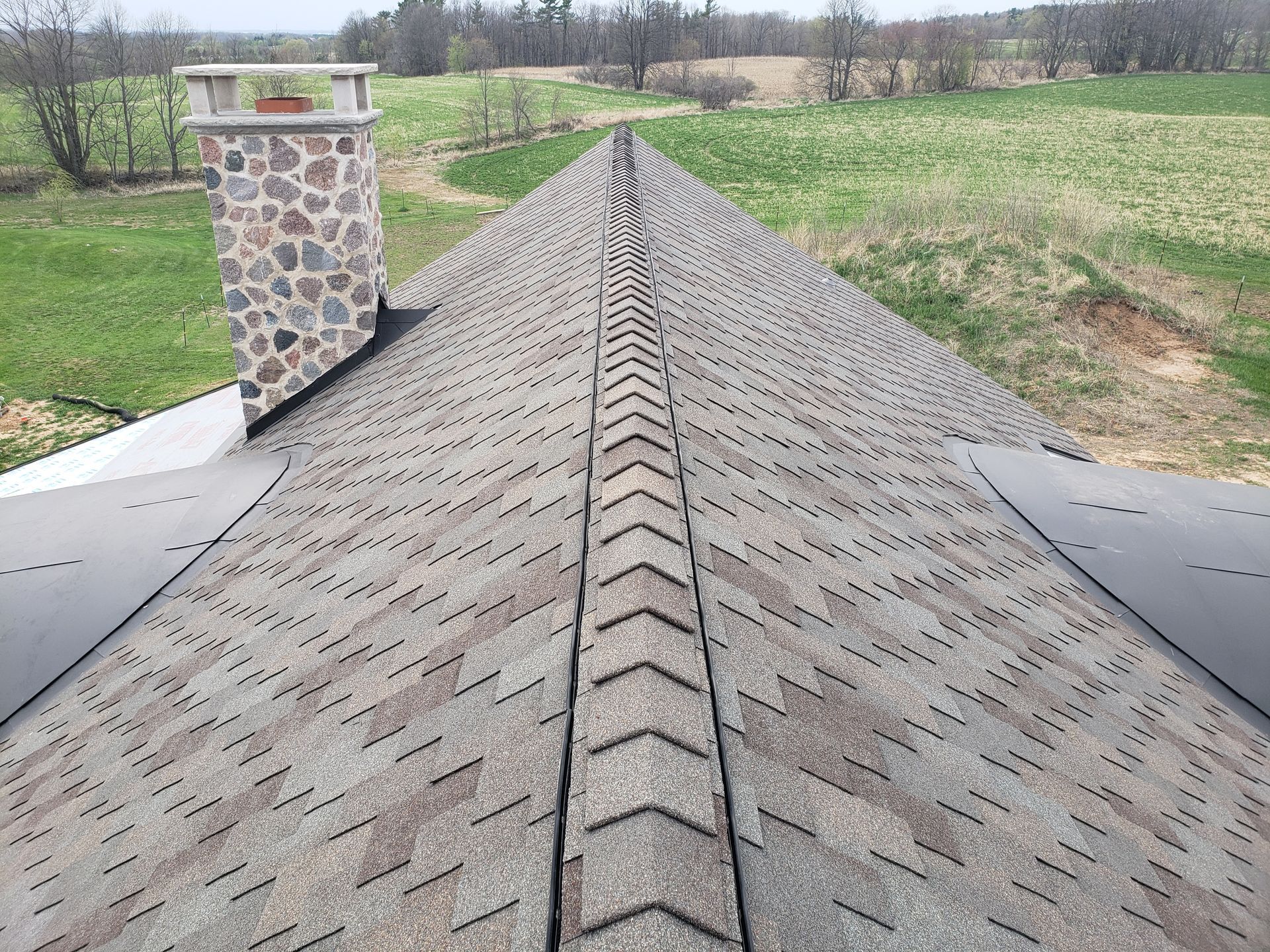A roof with a chimney on it and a field in the background.