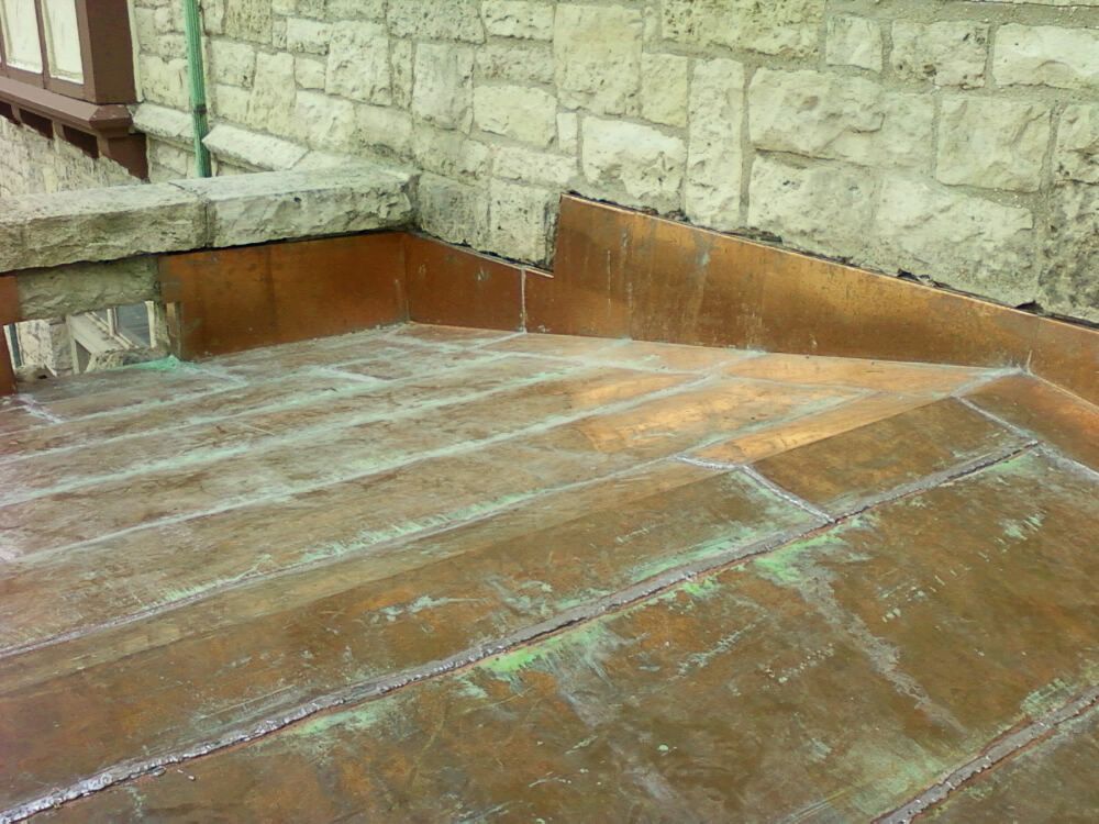 A brick wall with a copper roof in front of it