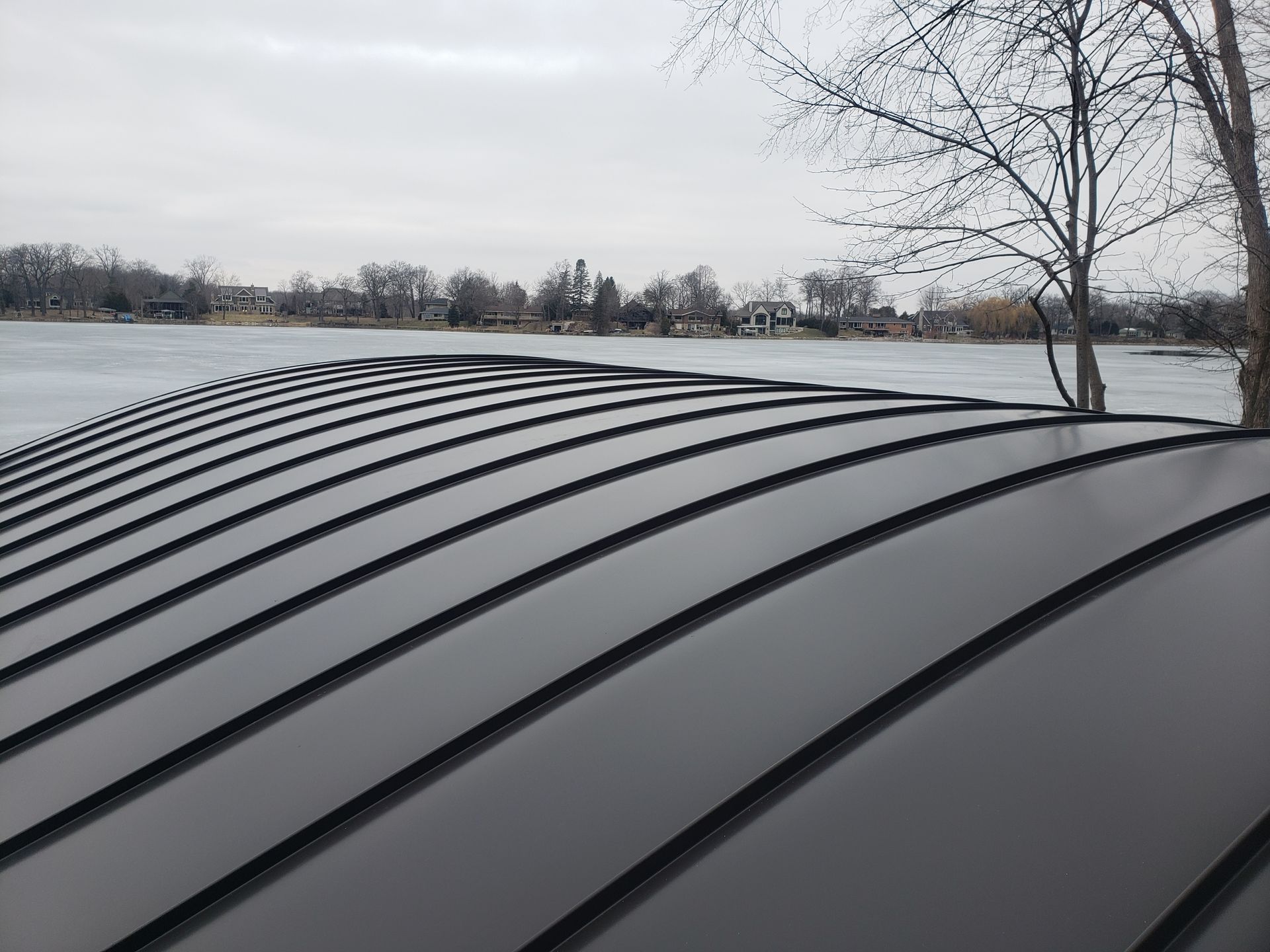 A black metal roof with a lake in the background