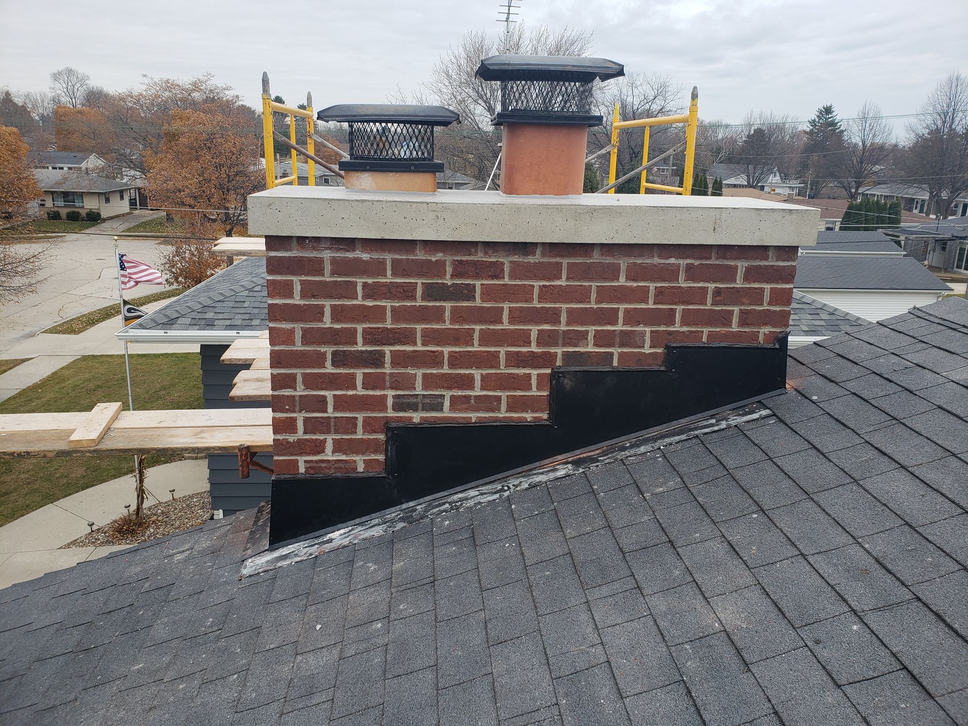 A brick chimney is sitting on top of a roof.