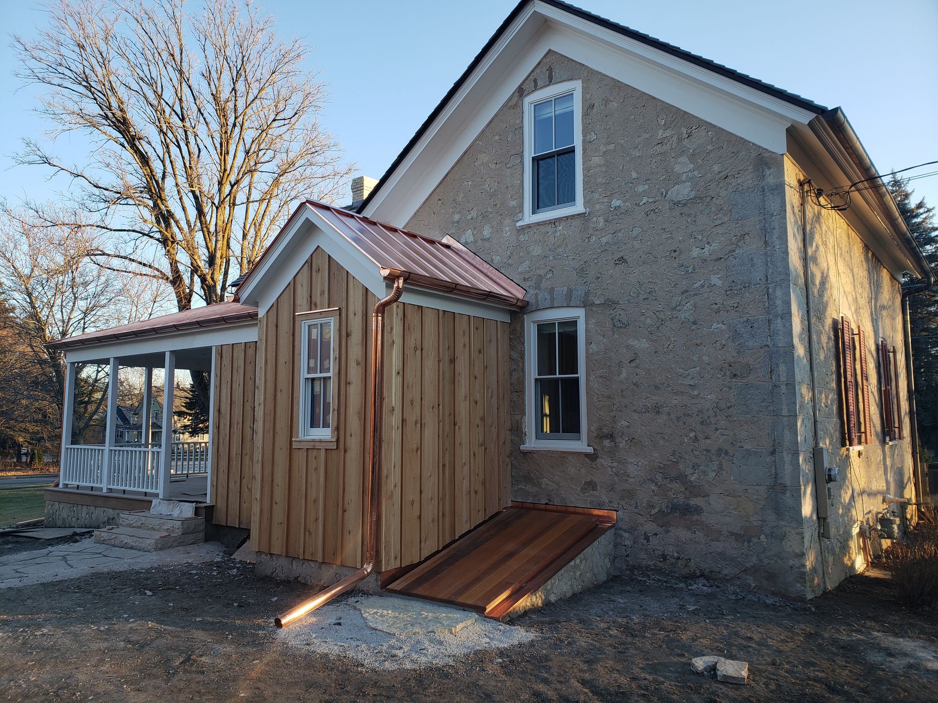 A stone house with a wooden shed attached to it