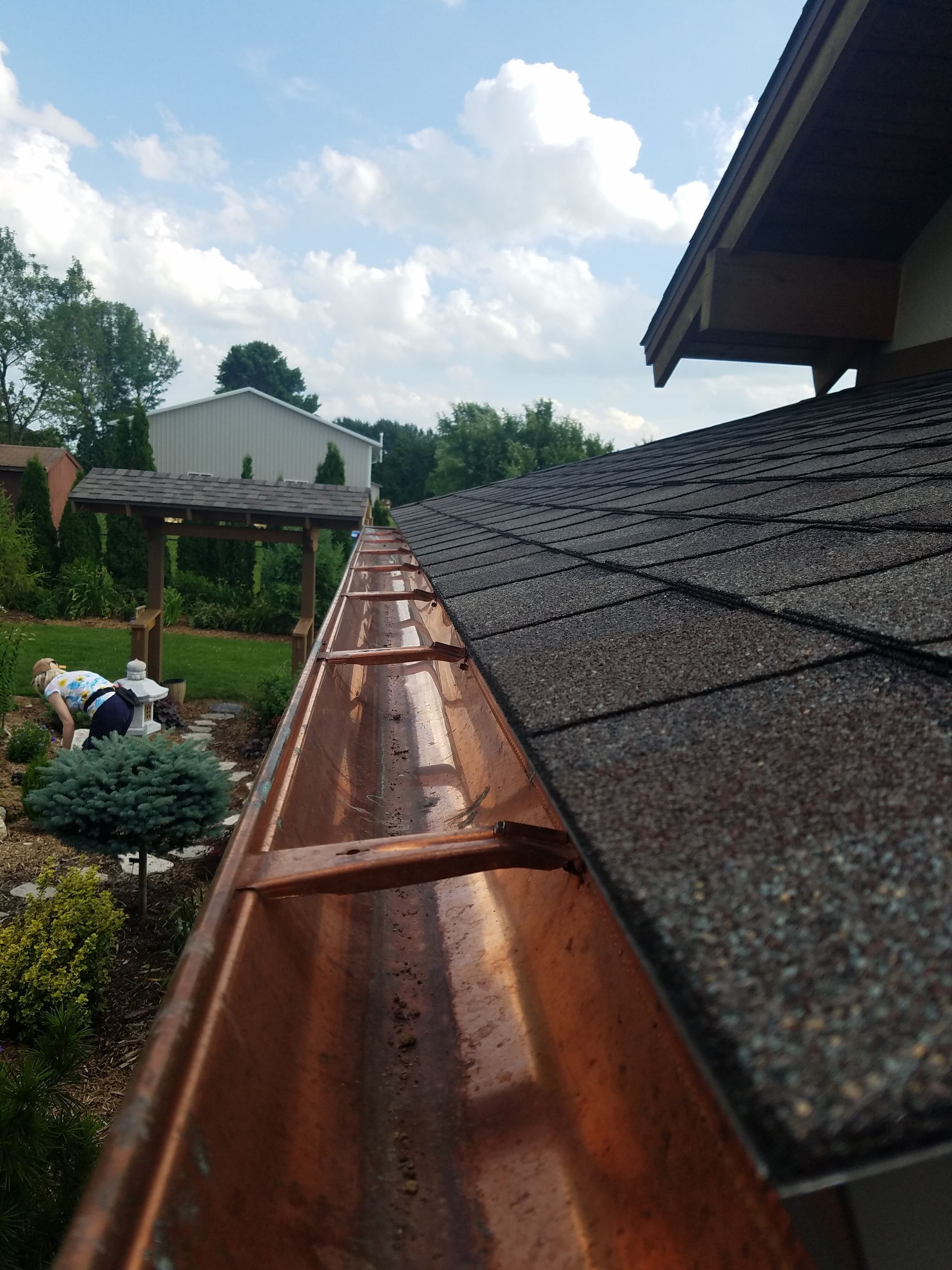 A copper gutter is attached to the roof of a house