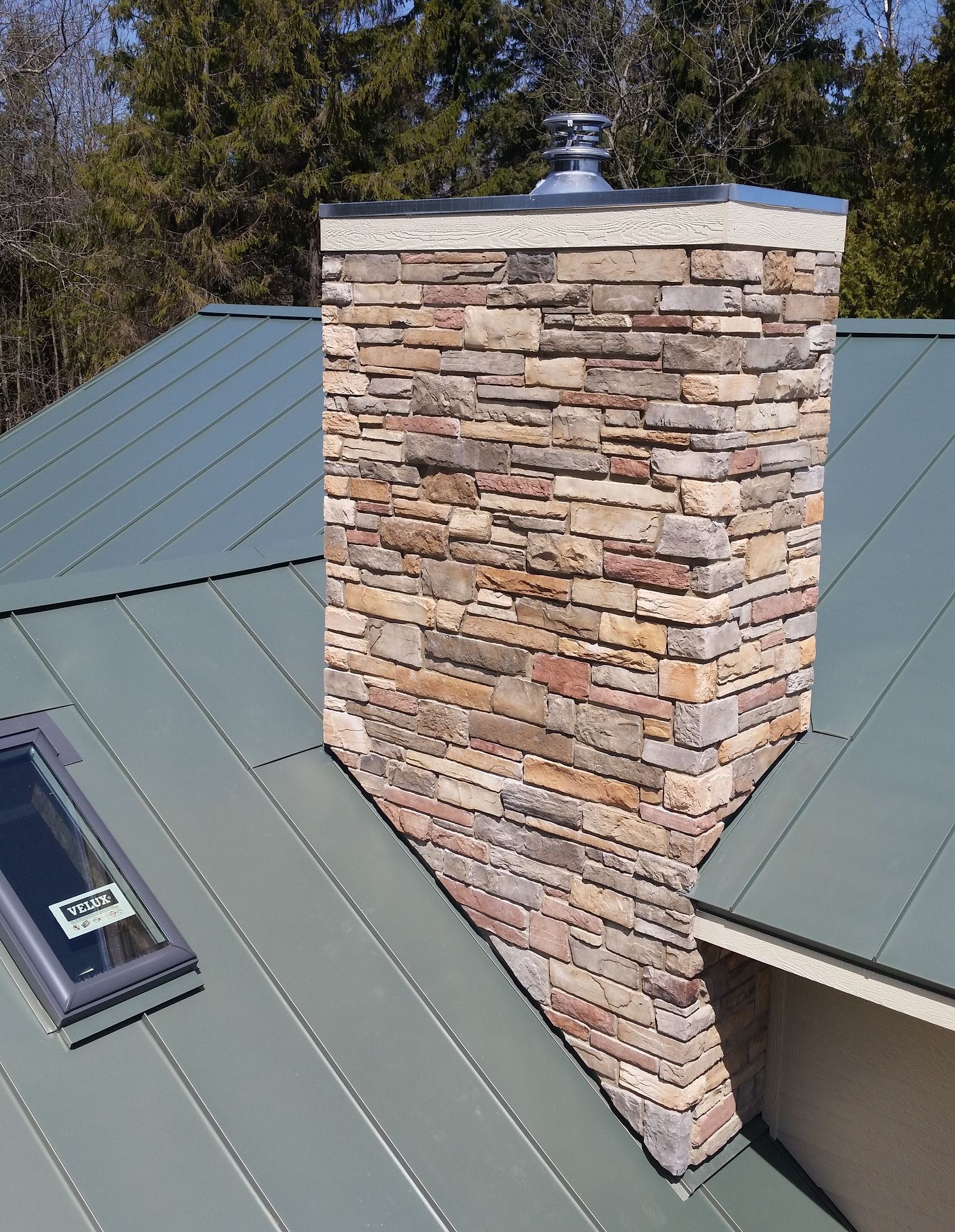 A brick chimney on top of a green roof