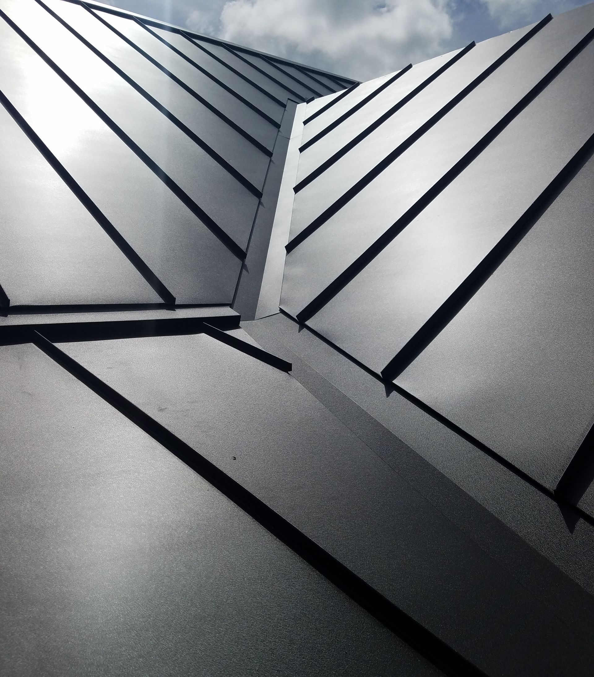 A close up of a black roof with a blue sky in the background