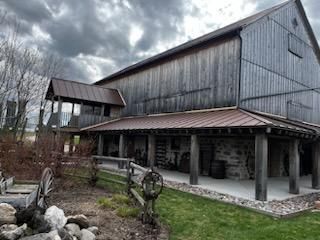 A large barn with a porch and a wagon wheel in front of it.