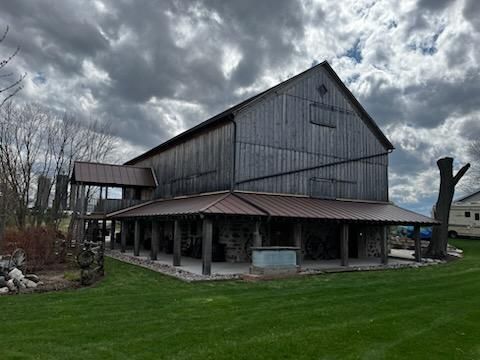 A large barn with a metal roof is sitting on top of a lush green field.