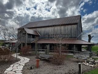 A large wooden barn with a metal roof and a stone path leading to it.