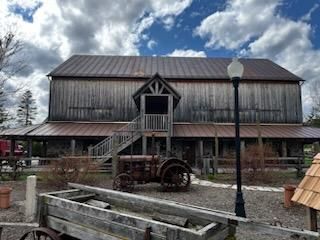 An old barn with a tractor and wagon in front of it.