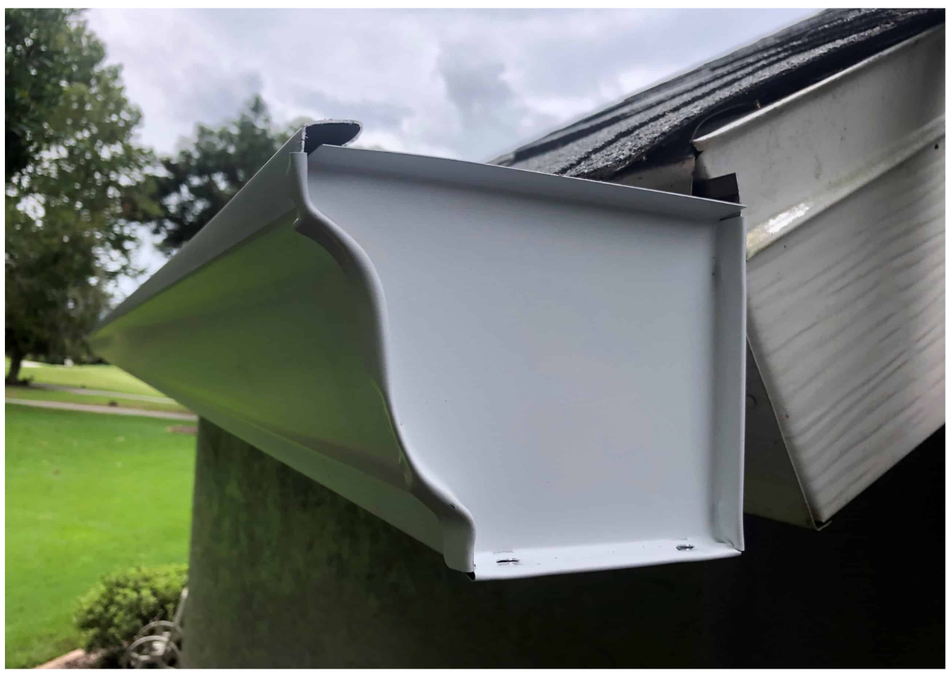 A white k-style gutter is attached to the side of a house.