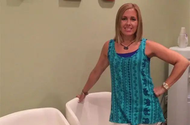 A woman in a blue tank top is standing in a waiting room.