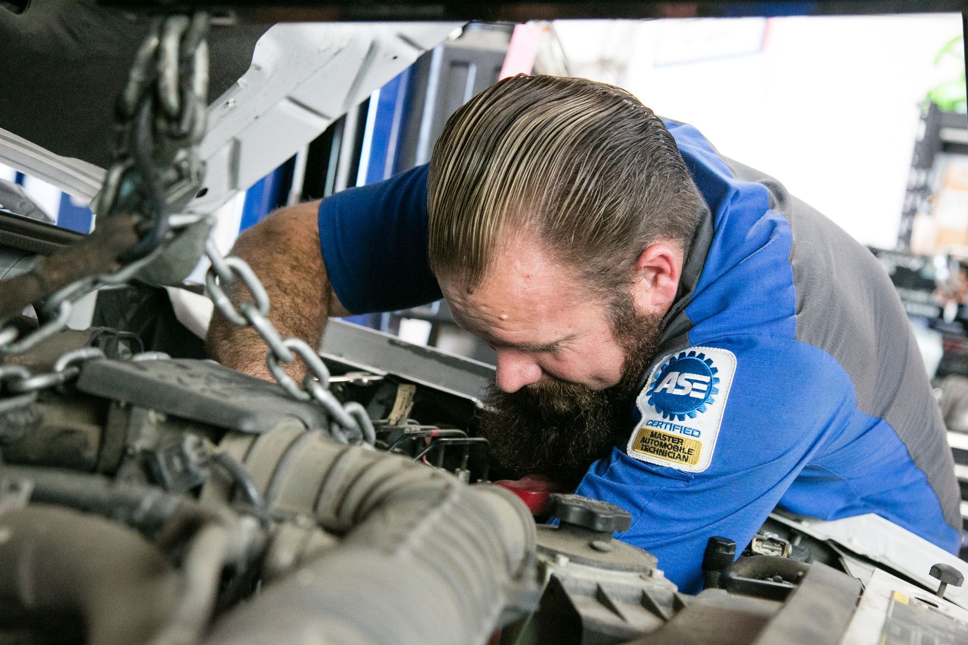 Man with ASE Certified Badge performing repair on vehicle | Shift'N Gears Auto Repair