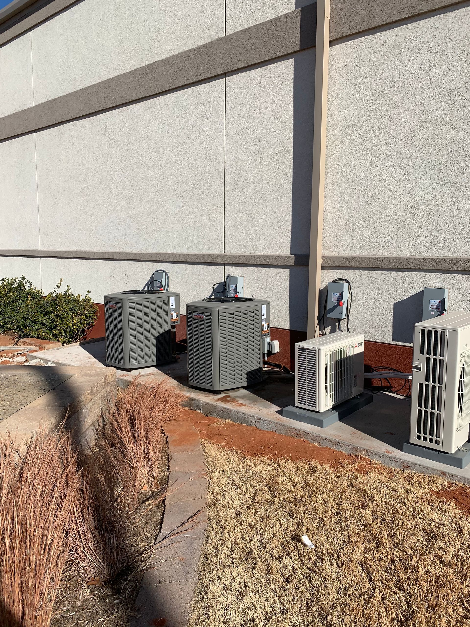 Three air conditioners are sitting outside of a building