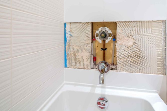 A bathtub is being remodeled in a bathroom with a hole in the wall.