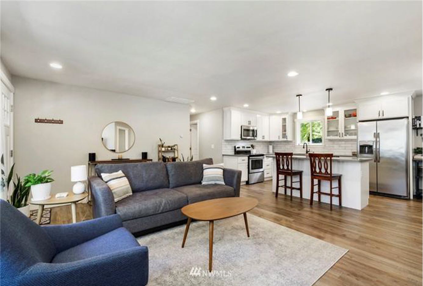 A living room with a couch , chair , coffee table and kitchen.