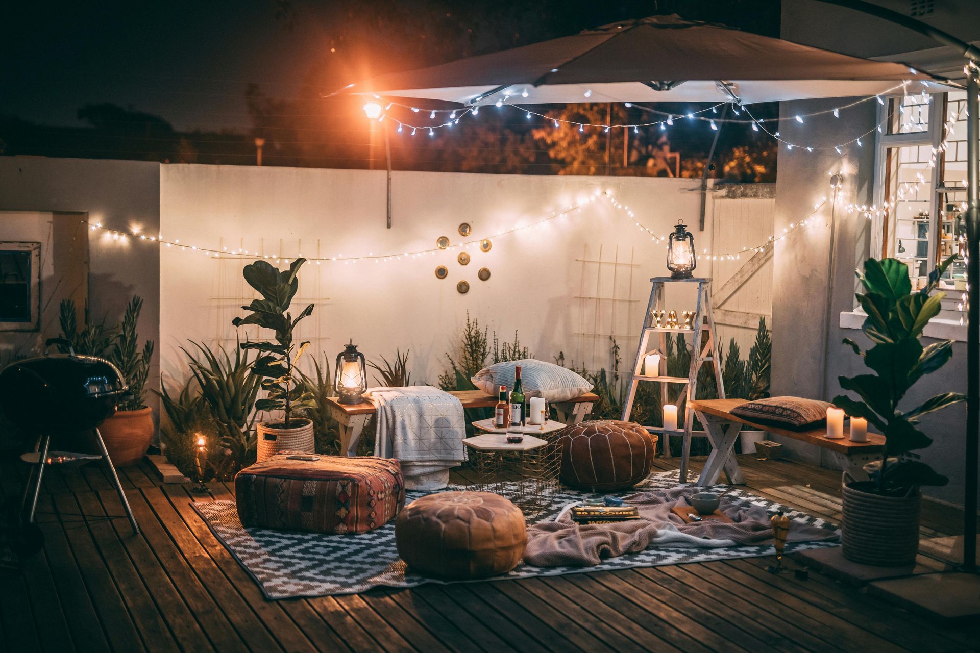 A patio with a lot of furniture and lights at night.