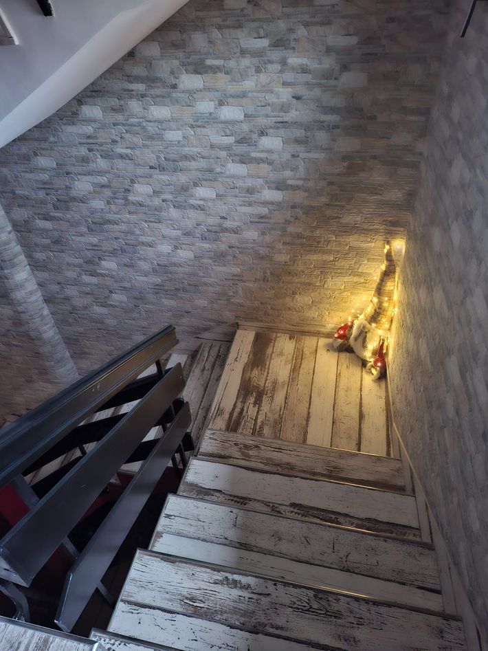 Ripida scalinata con muri in pietra e un piccolo albero decorativo illuminato sul pianerottolo inferiore.