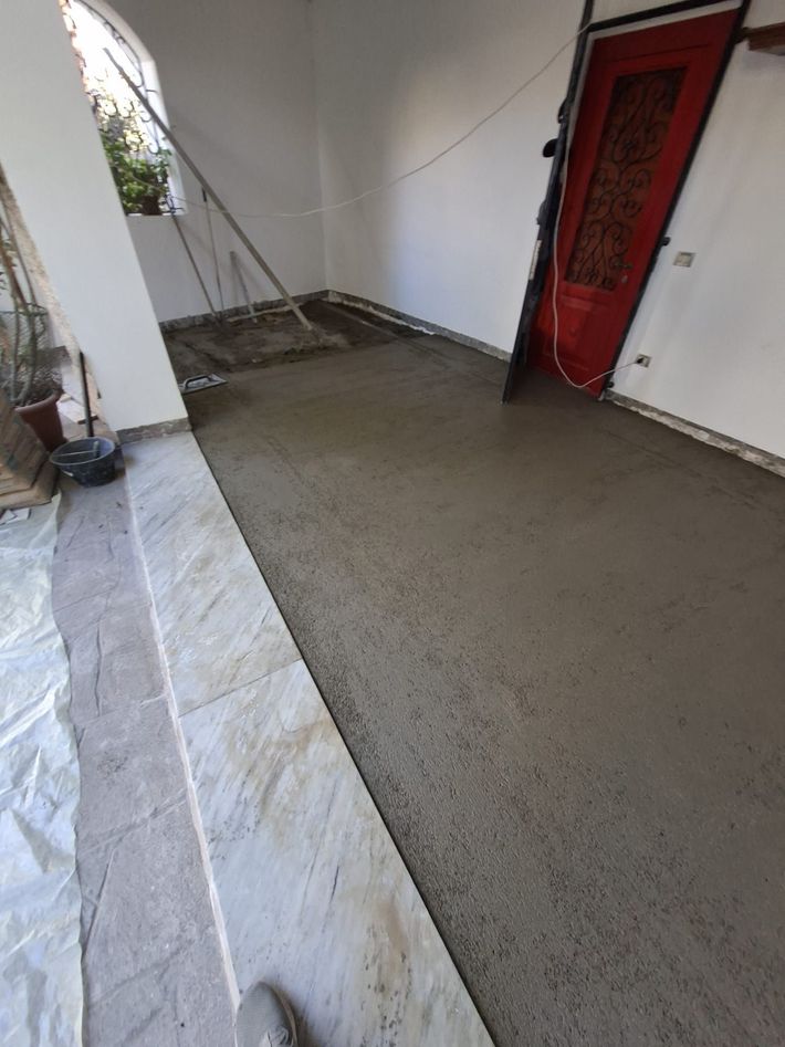 Portico appena cementato accanto a una porta rossa e pareti bianche