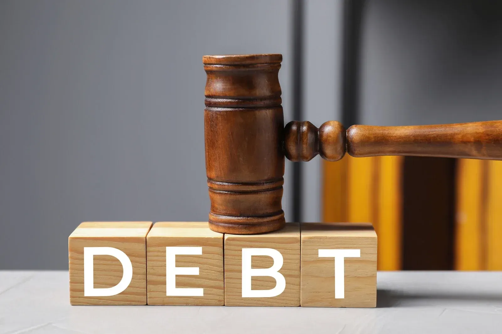 A wooden judge's gavel rests on four wooden blocks arranged in a row, spelling the word 