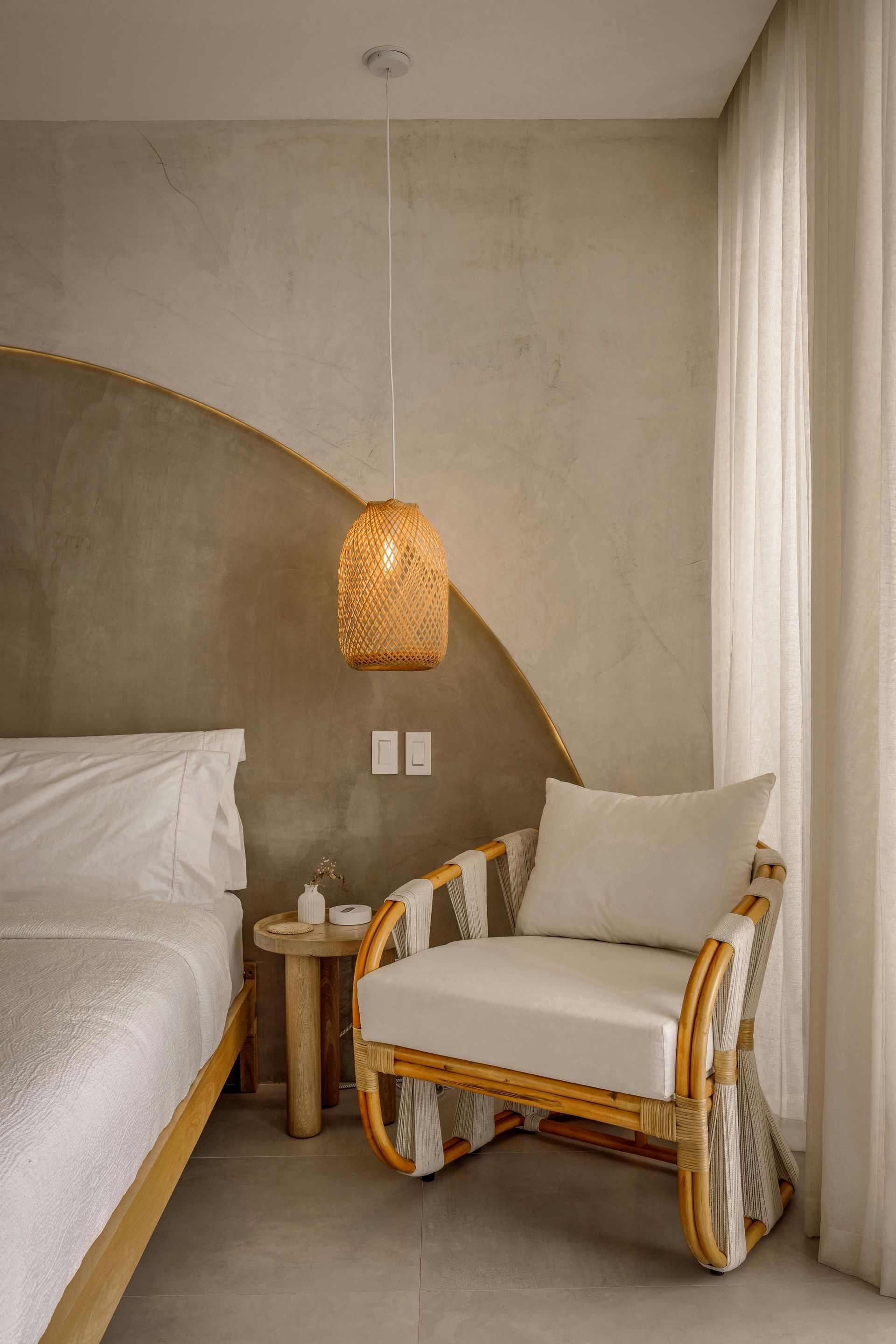 Bedroom with a wicker chair, rattan pendant light, and textured wall with a gold accent.
