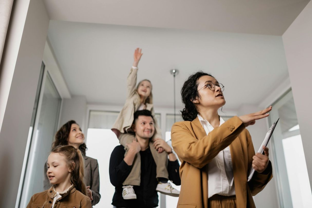 Real estate agent showing a family an apartment, pointing upward.