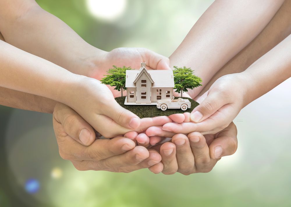 Hands Cradling a Miniature House With Trees and a Car — Kellie O'Malley Conveyancing In Lake Munmorah, NSW
