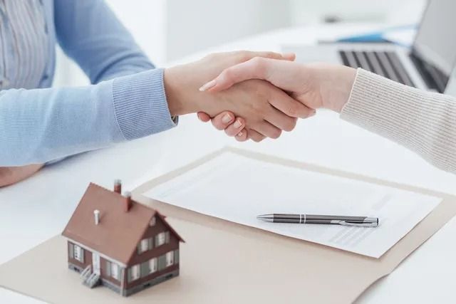 Two People Shaking Hands Over a Real Estate Contract — Kellie O'Malley Conveyancing In Lake Macquarie, NSW