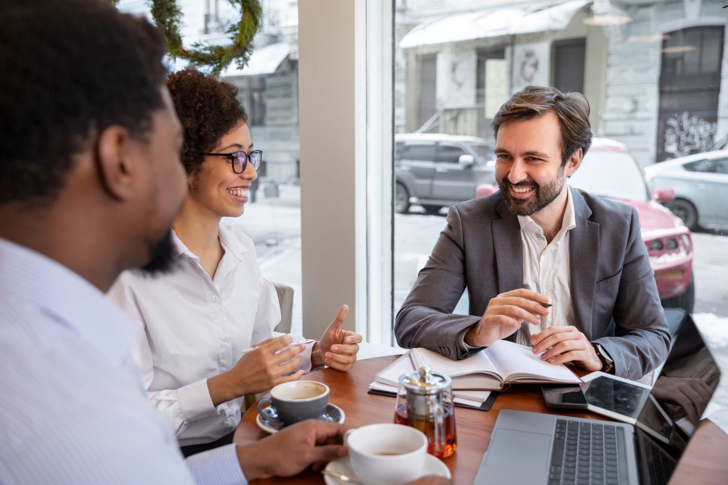 Three people having a business meeting in a cafe, talking and smiling.
