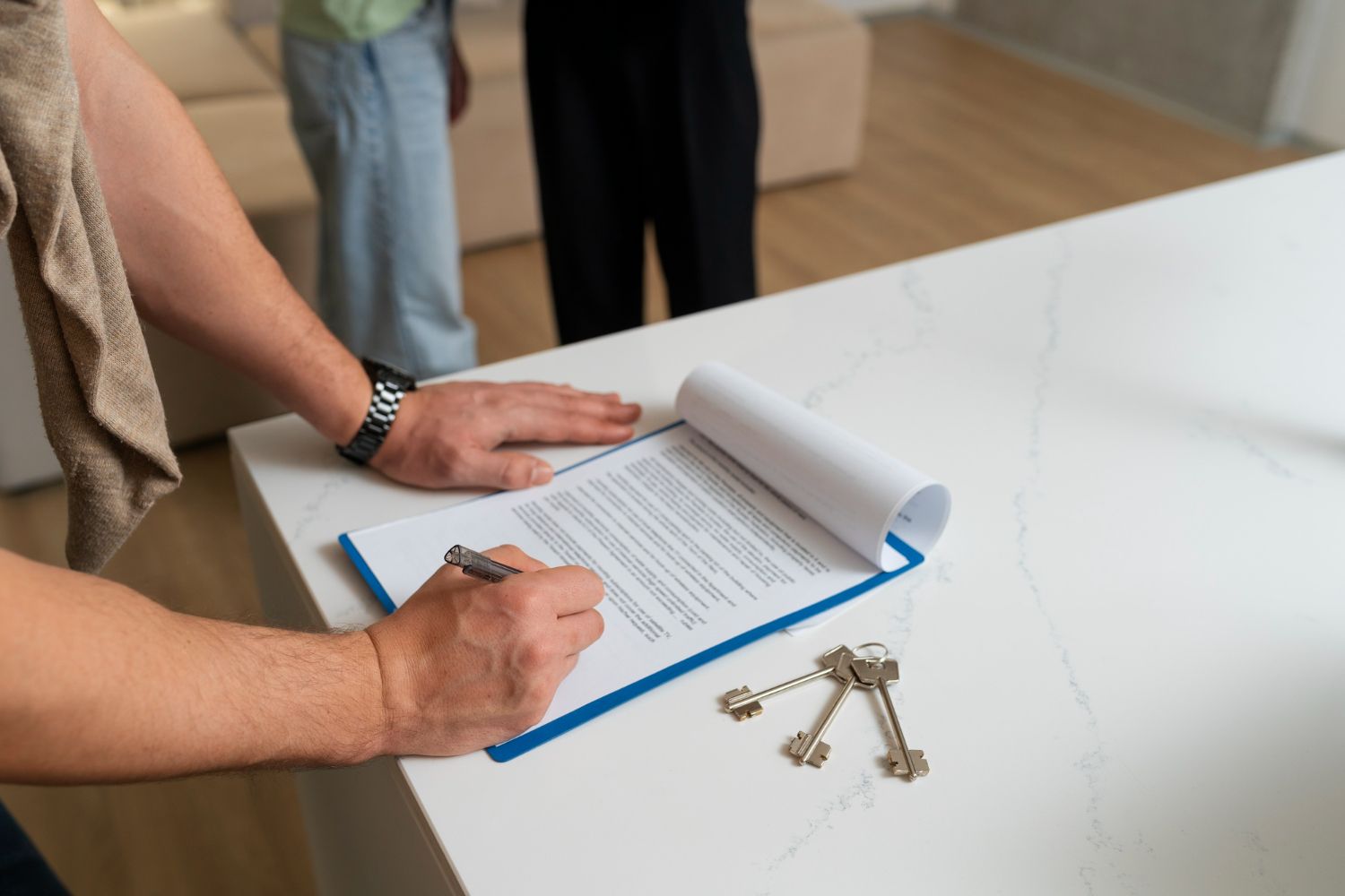 Person signing document on a clipboard, keys and people in background.