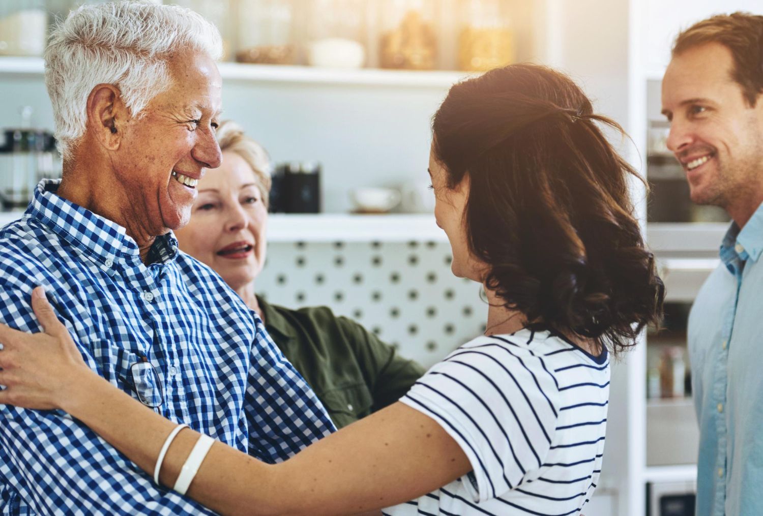 Family gathering, embracing and smiling in a well-lit kitchen.