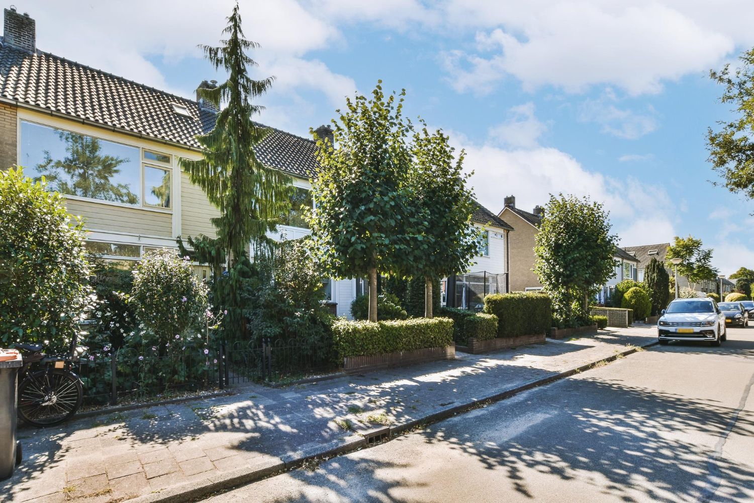 Row of houses with trees and cars on a sunny street.