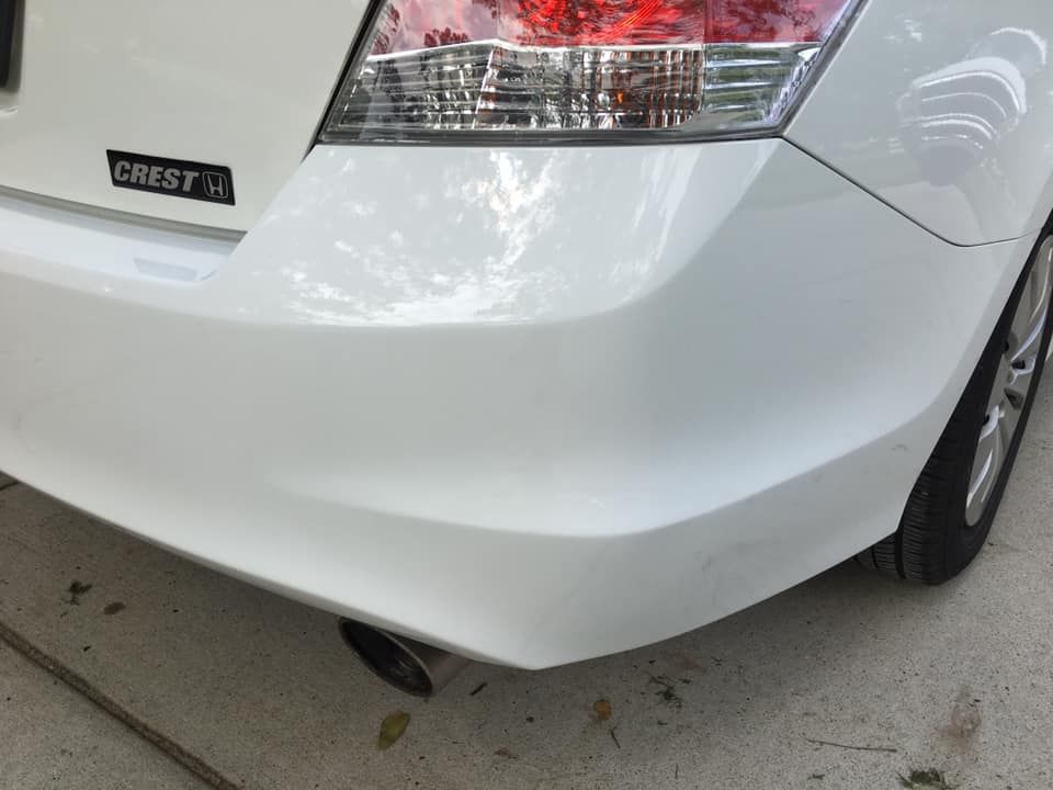 a white car with a crest sticker on the back bumper