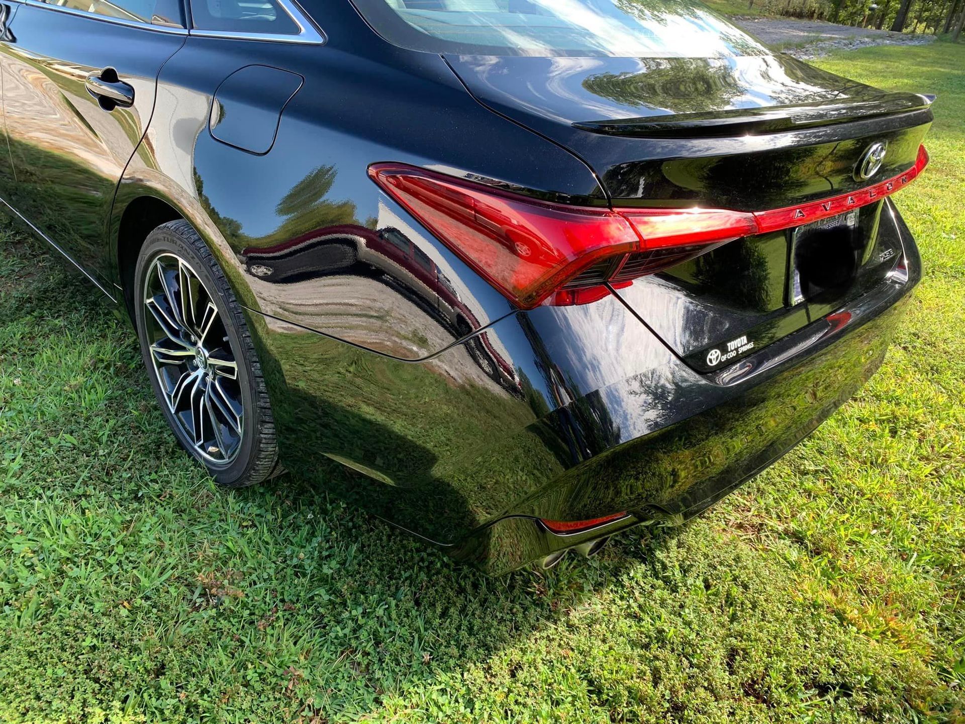 the back end of a black car is parked in the grass .