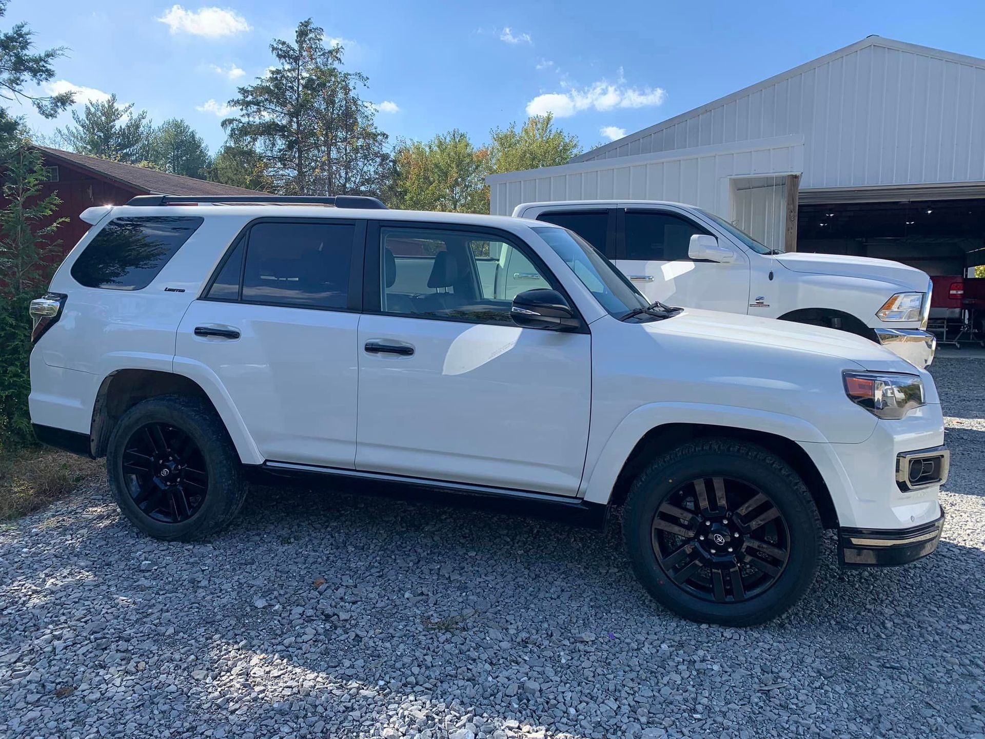 a white suv is parked in a gravel lot in front of a garage .