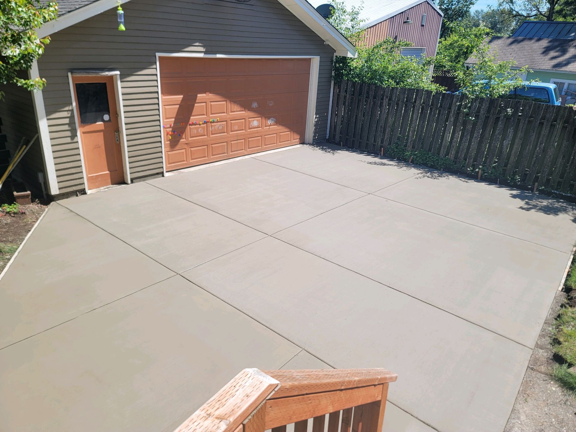 A concrete driveway leading to a garage with a fence in the background.
