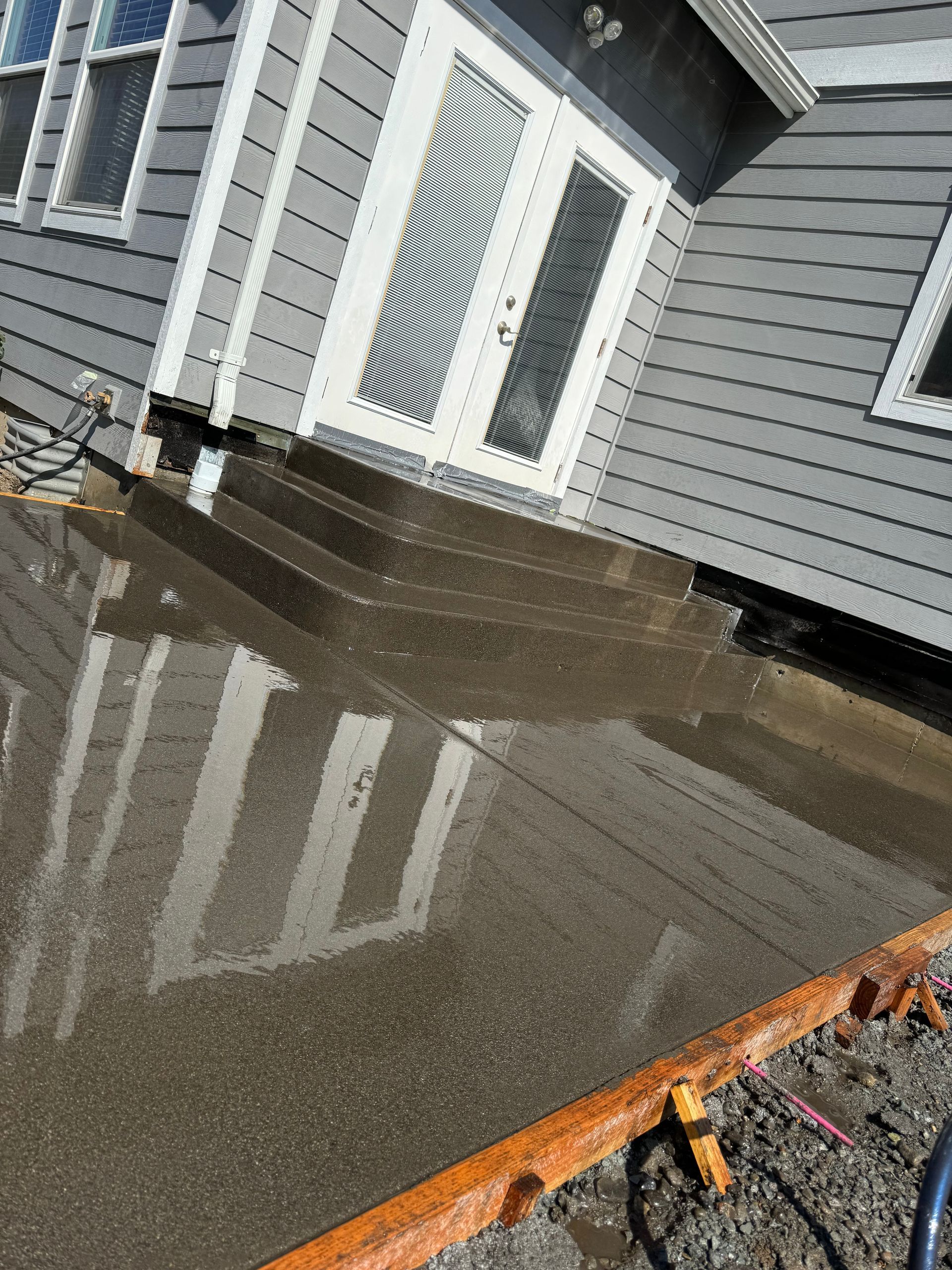 A concrete patio is being built in front of a house