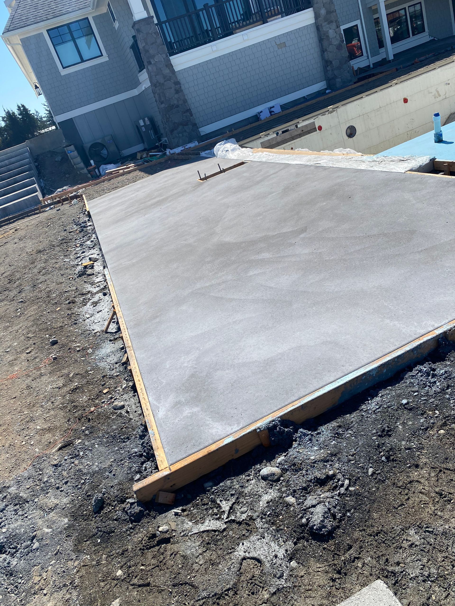 A concrete slab is sitting in the dirt next to a swimming pool.