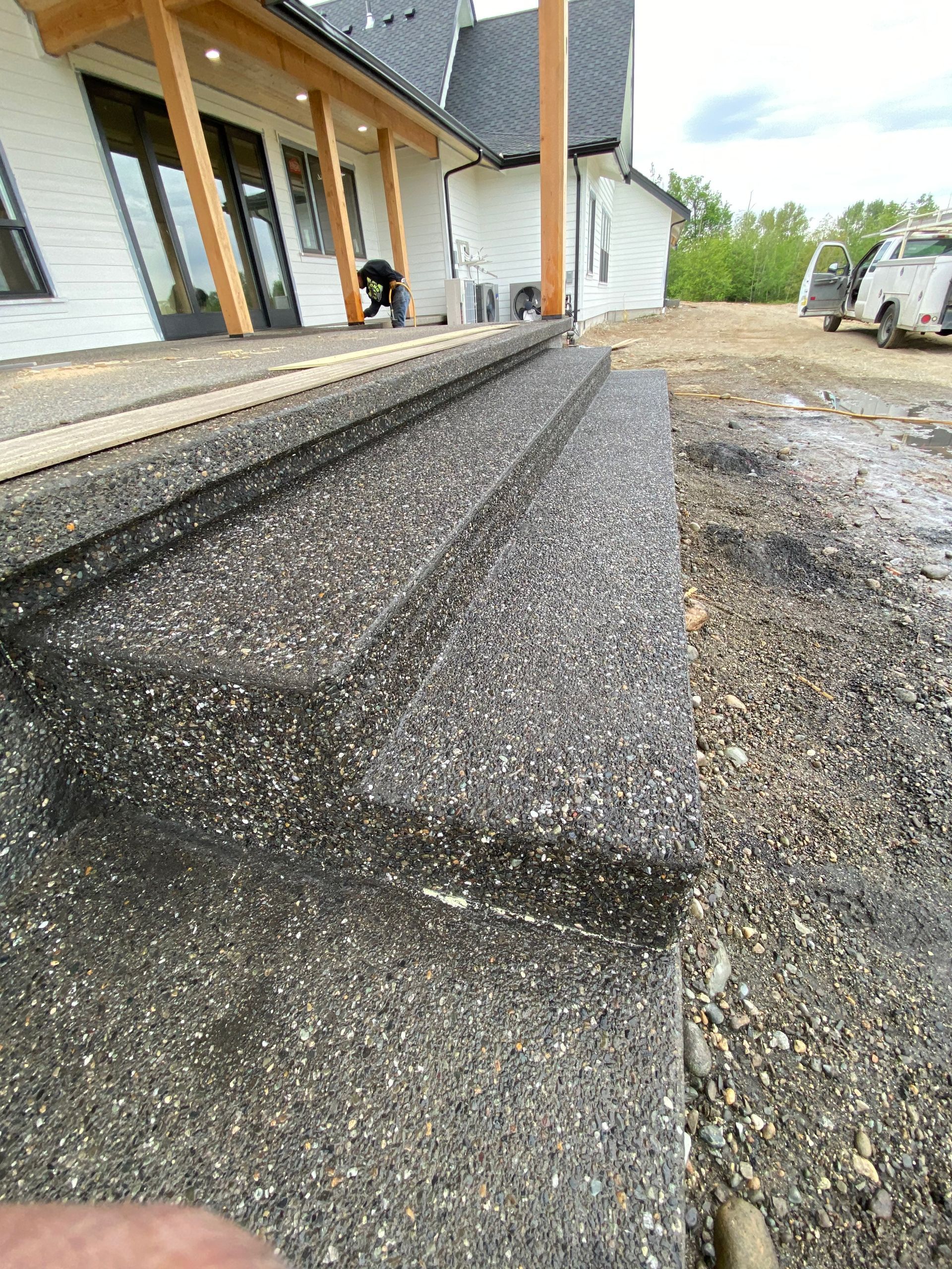 A person is working on a concrete patio in front of a house.