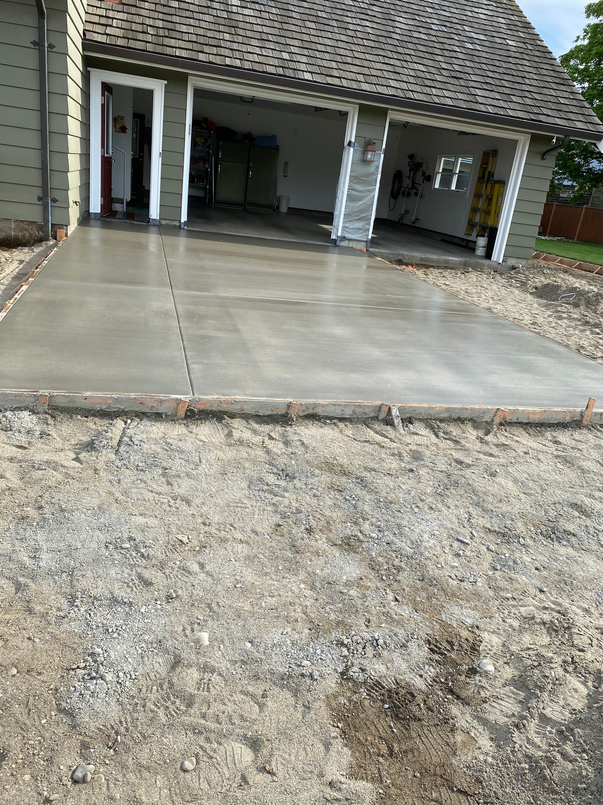 A concrete driveway is being built in front of a house.